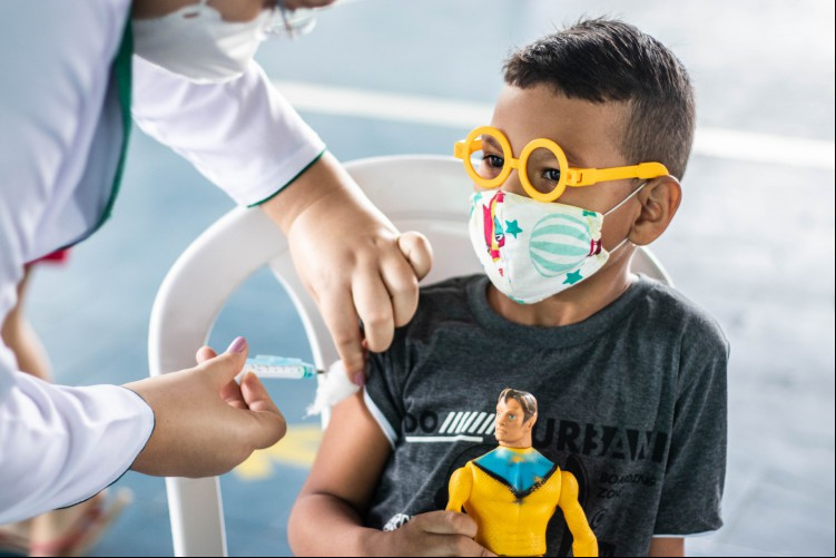 Pedro Miguel, 7 anos, levou um boneco de super-herói para dar "coragem e força" na hora de tomar a vacina.