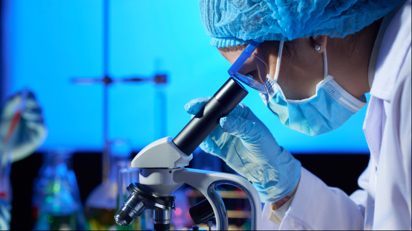 Pesquisador analisando amostra no microscópio em laboratório