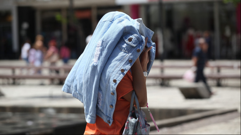 Semana Santa de 2025 pode contar com redução das chuvas e aumento das temperaturas, segundo a Funceme. Na imagem, pedestre se protege contra o sol na Praça do Ferreira, em Fortaleza